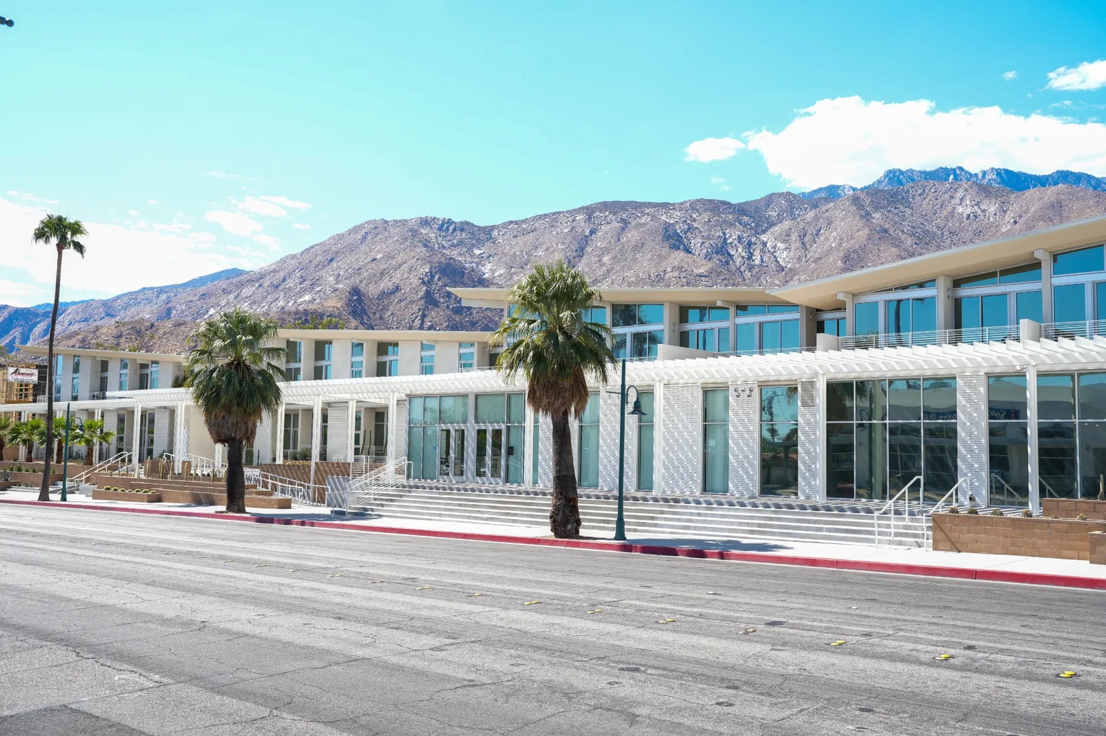 Glazed building with white pergolas and mountains behind it